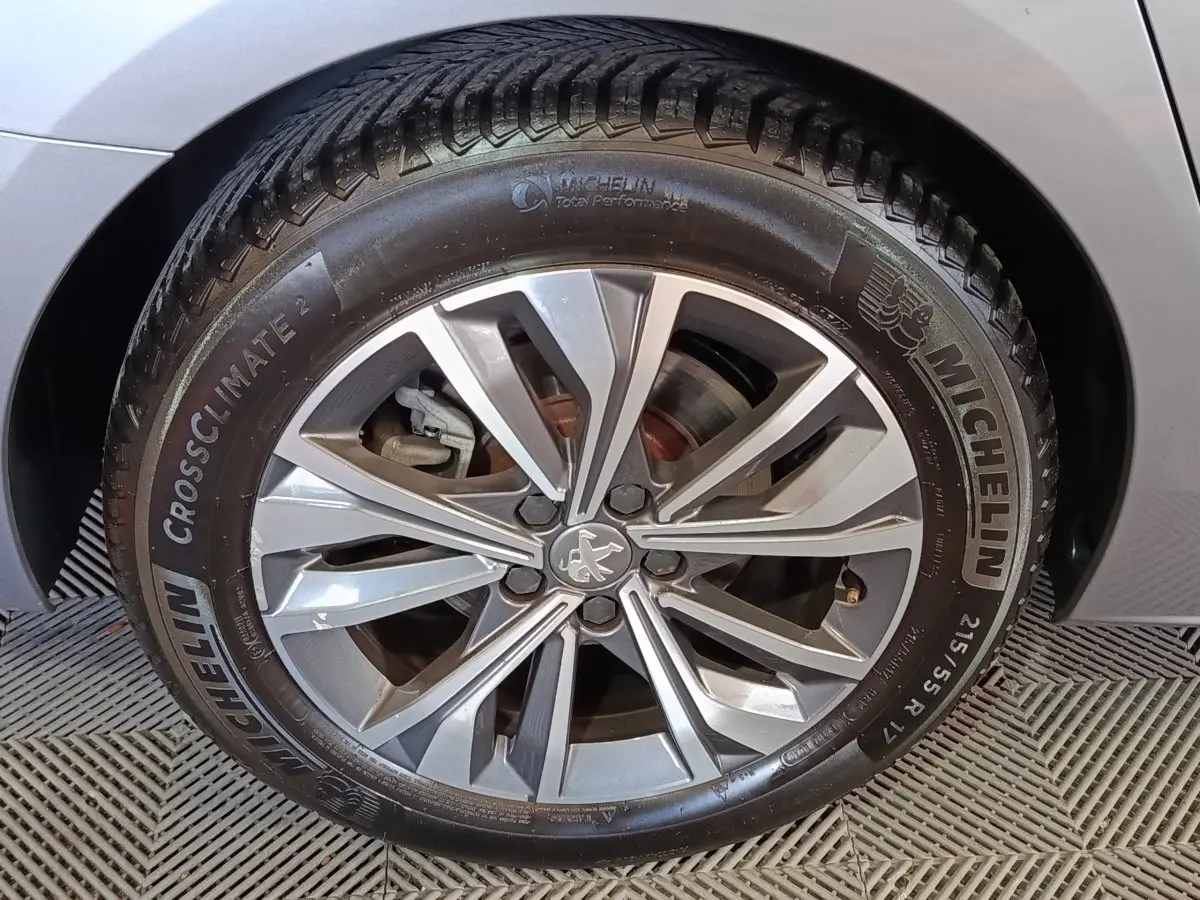 Gros plan sur la roue avant droite gris clair d'une Peugeot 508 avec jante alliage et pneu Michelin CrossClimate 2.
