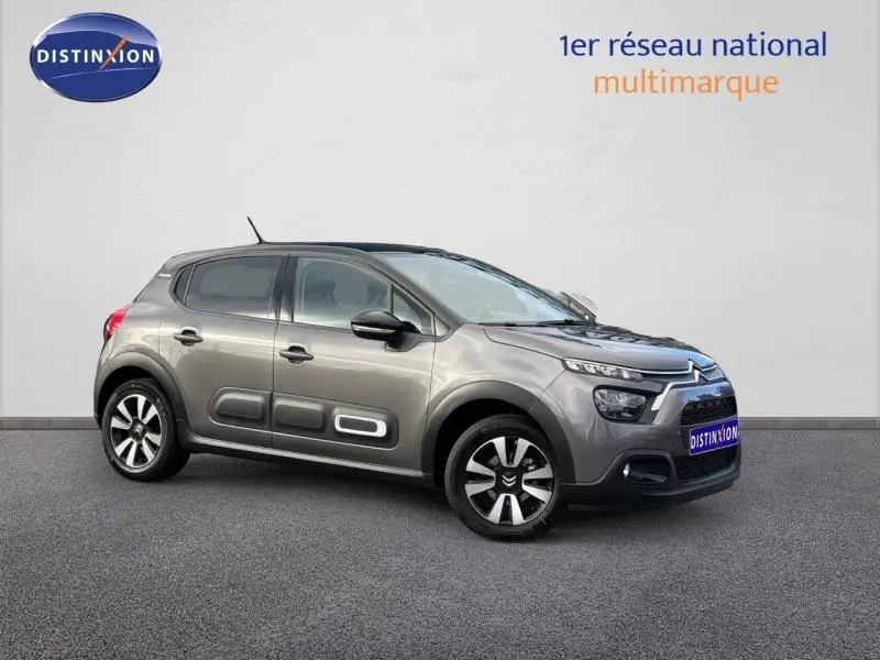 Citroën C3 2023 gris Platinium vue 3/4 avant droit avec inserts noirs et protections latérales blanches.
