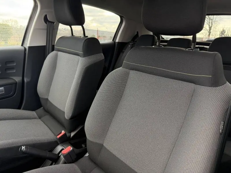 Vue intérieure rapprochée des sièges avant gris et noirs de la Citroën C3 1.2 PureTech 2023 avec surpiqûres jaunes.