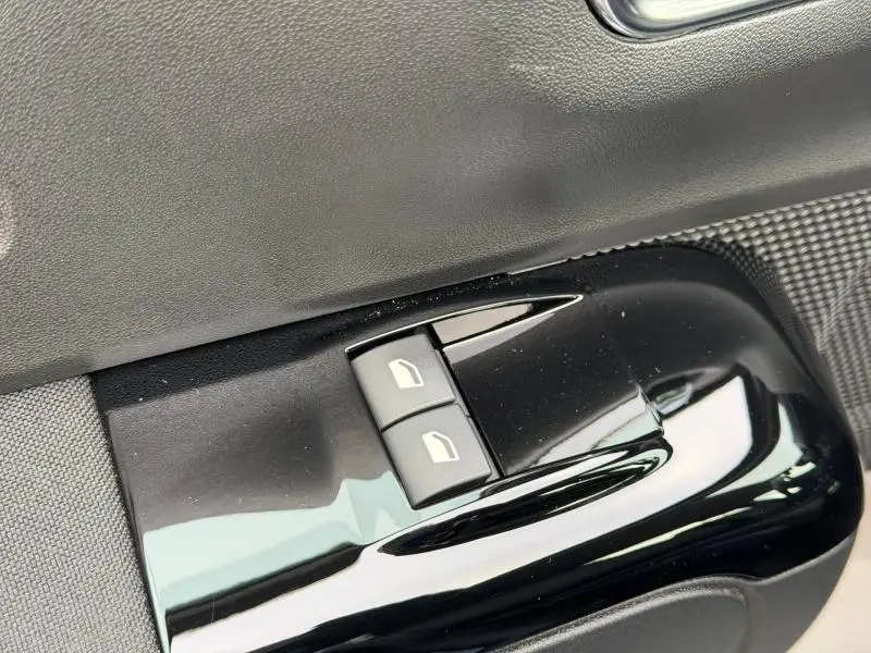 Gros plan sur les commandes de lève-vitres côté gauche intérieur d'une Citroën C3 2023 en Gris Platinium et Noir Perla Nera.