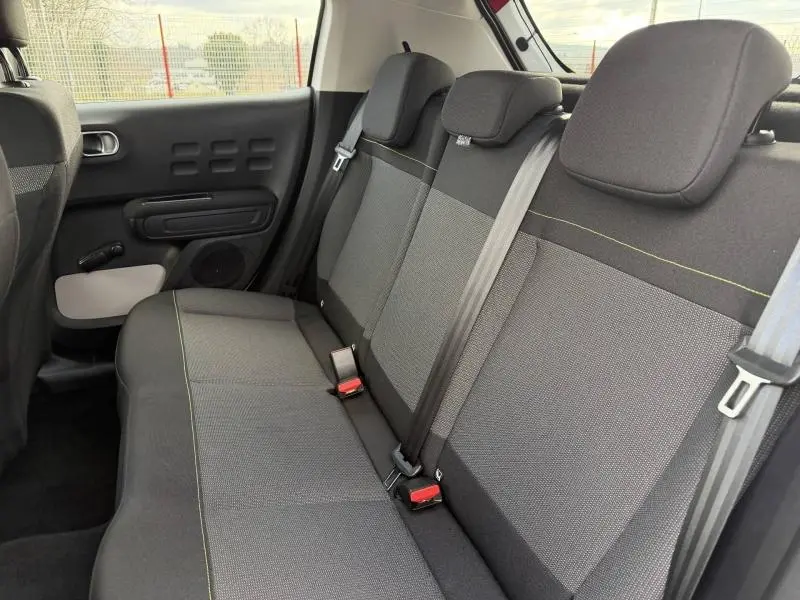 Vue intérieure des sièges arrière de la Citroën C3 2023, tissu gris avec surpiqûres jaunes et ceinture de sécurité noire.