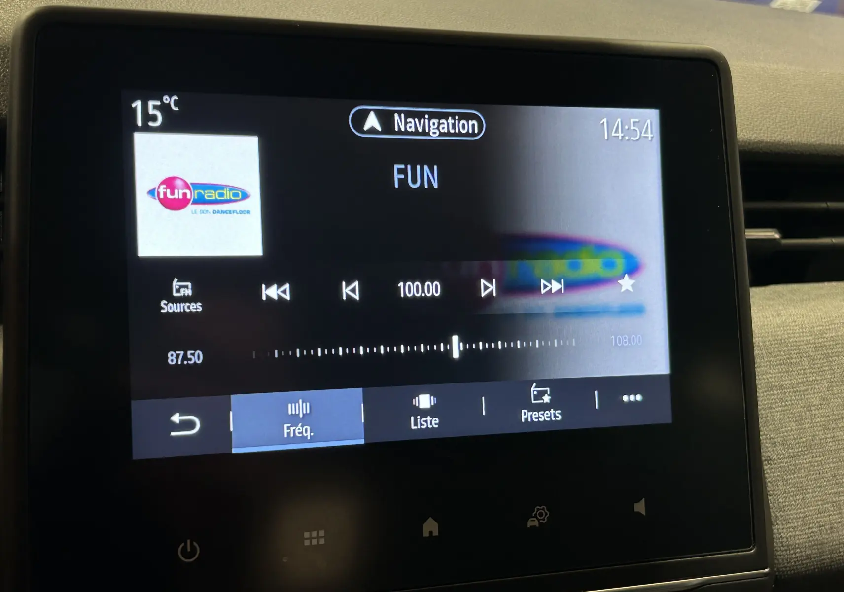 Écran tactile central de la Renault Clio V blanc montrant la radio sur la fréquence 100 FM avec navigation active.