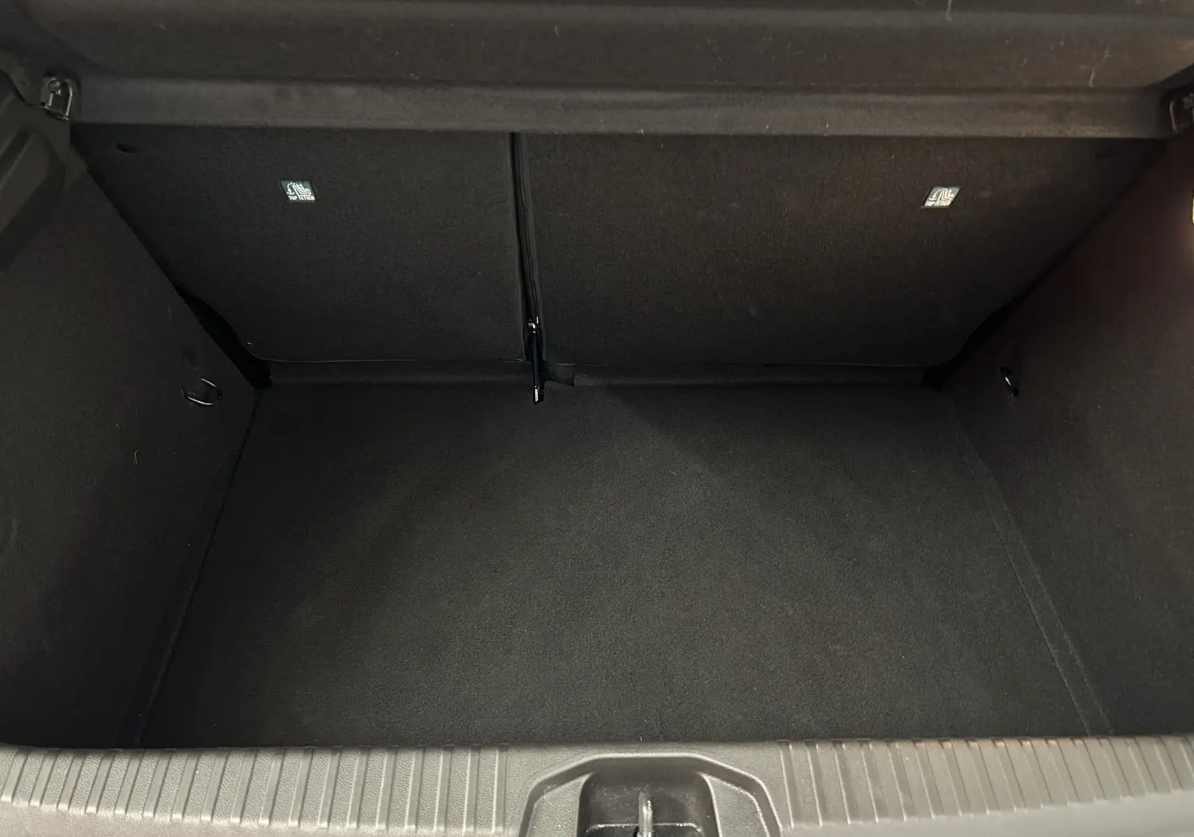 Coffre vide en vue plongeante d'une Renault Clio V blanche, montrant l'espace de chargement intérieur noir.