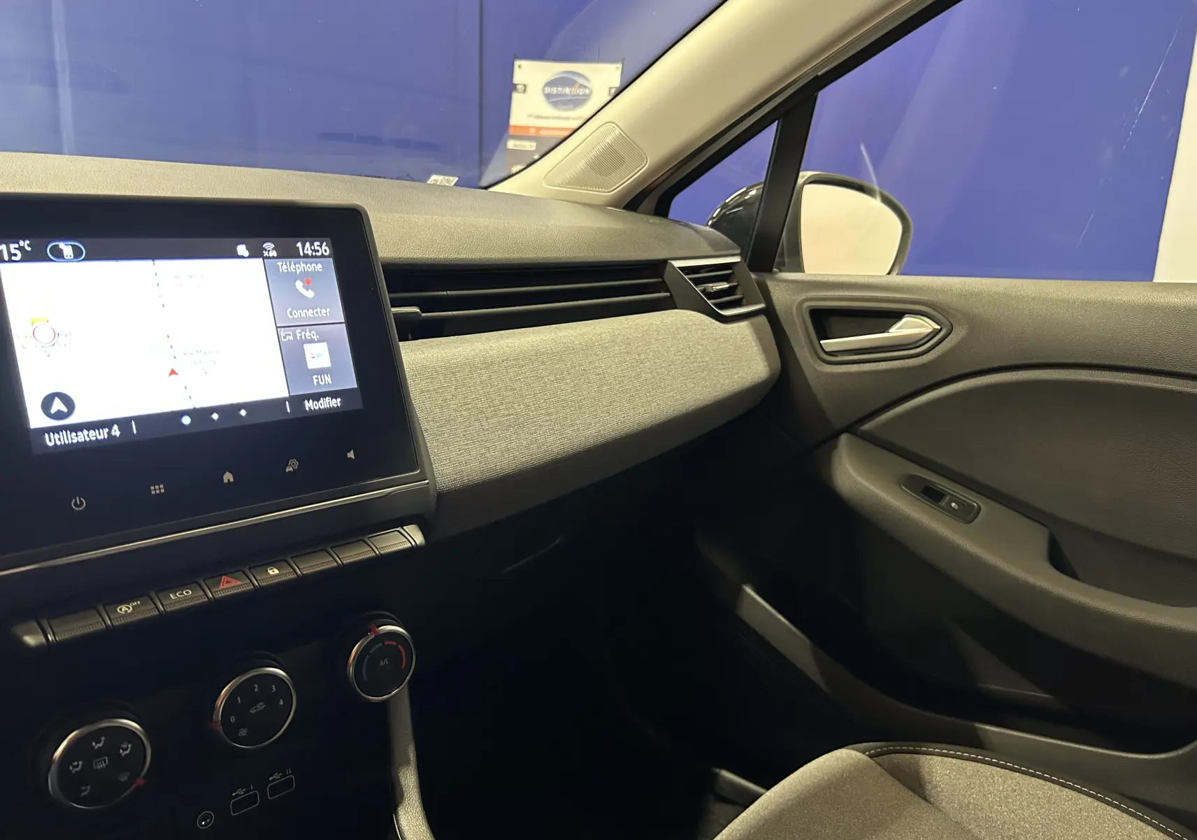 Intérieur avant droit de la Renault Clio V blanche, avec tableau de bord moderne et écran tactile GPS allumé.