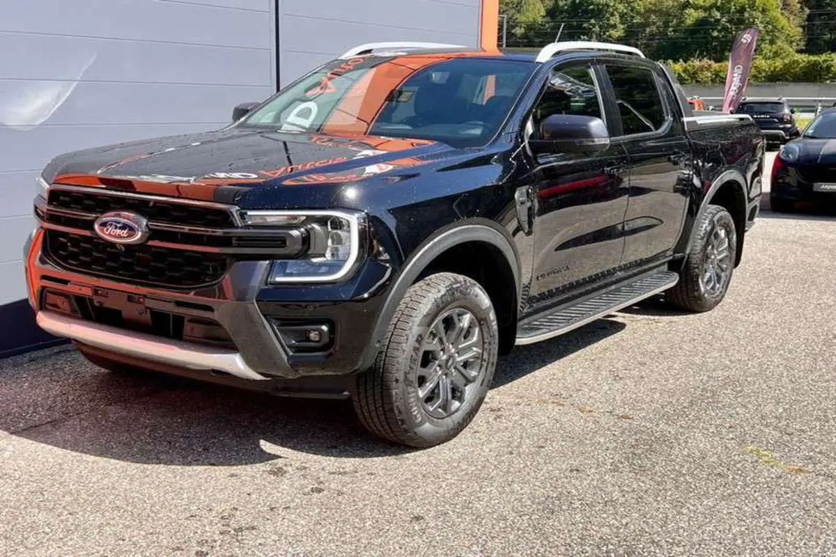 Ford Ranger 3.0 V6 Wildtrak Plus noir agate, vue 3/4 avant droit, avec jantes alu et marchepieds visibles.