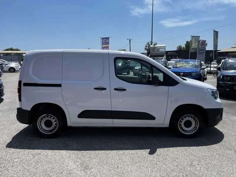 Vue de profil côté droit d’un utilitaire blanc Opel Combo Cargo 2024 avec bande noire latérale et roues acier.