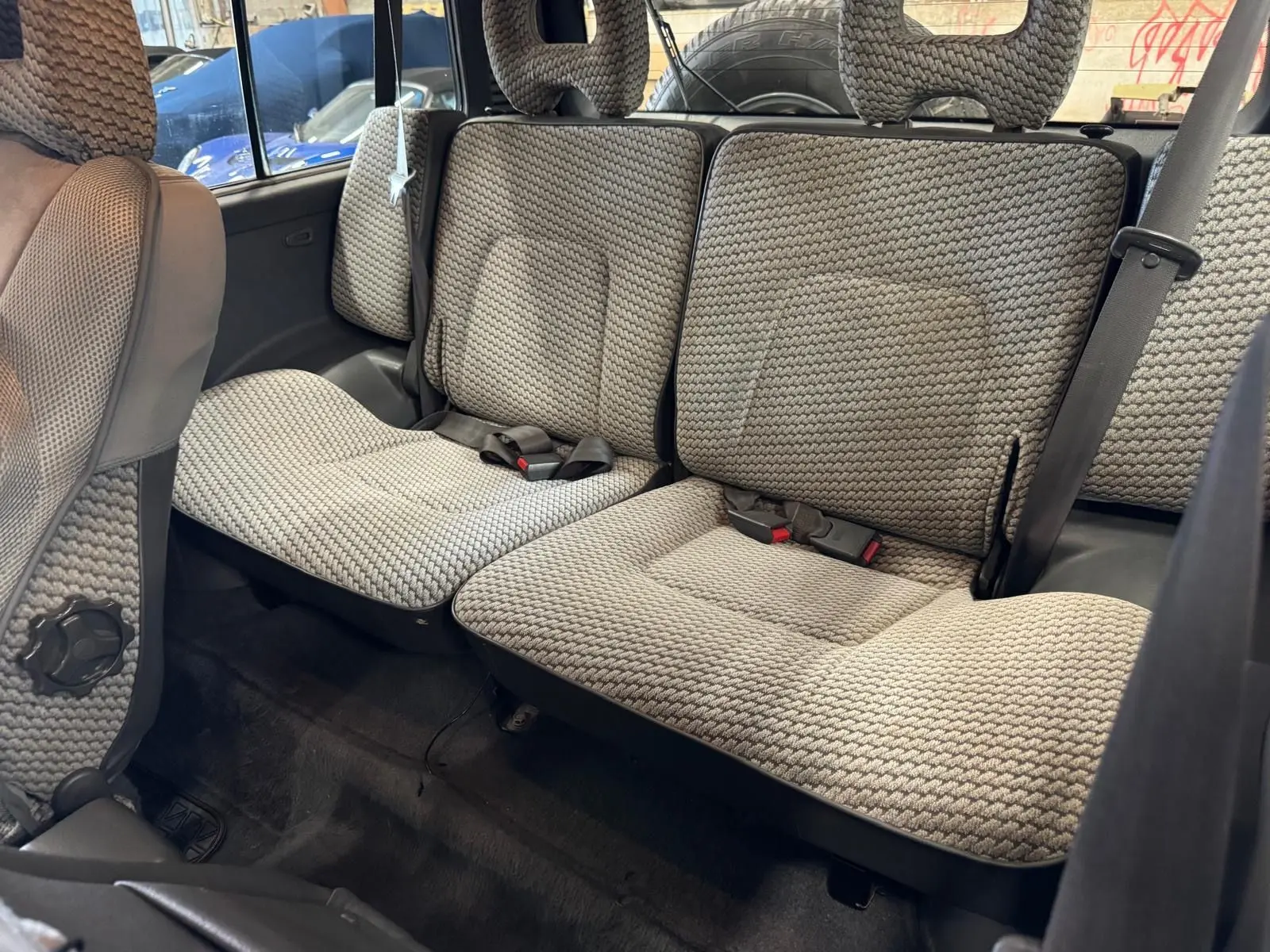 Vue intérieure arrière du Mitsubishi Pajero Court 2.8 TD 1997, sièges en tissu gris à motifs tressés.