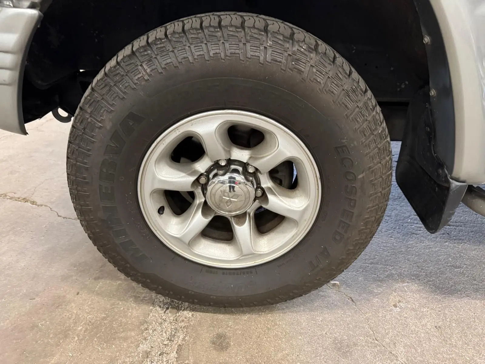 Gros plan sur la roue avant droite gris aluminium du Mitsubishi Pajero Court 2.8 TD avec jante alliage et marche-pied visible.