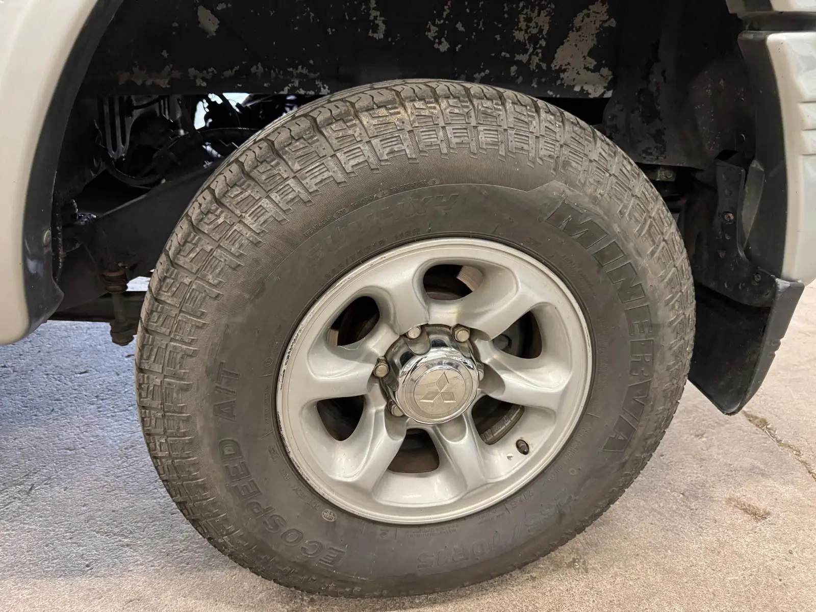 Gros plan sur la roue avant droite gris aluminium du Mitsubishi Pajero Court 2.8 TD avec jante alliage et logo central visible.