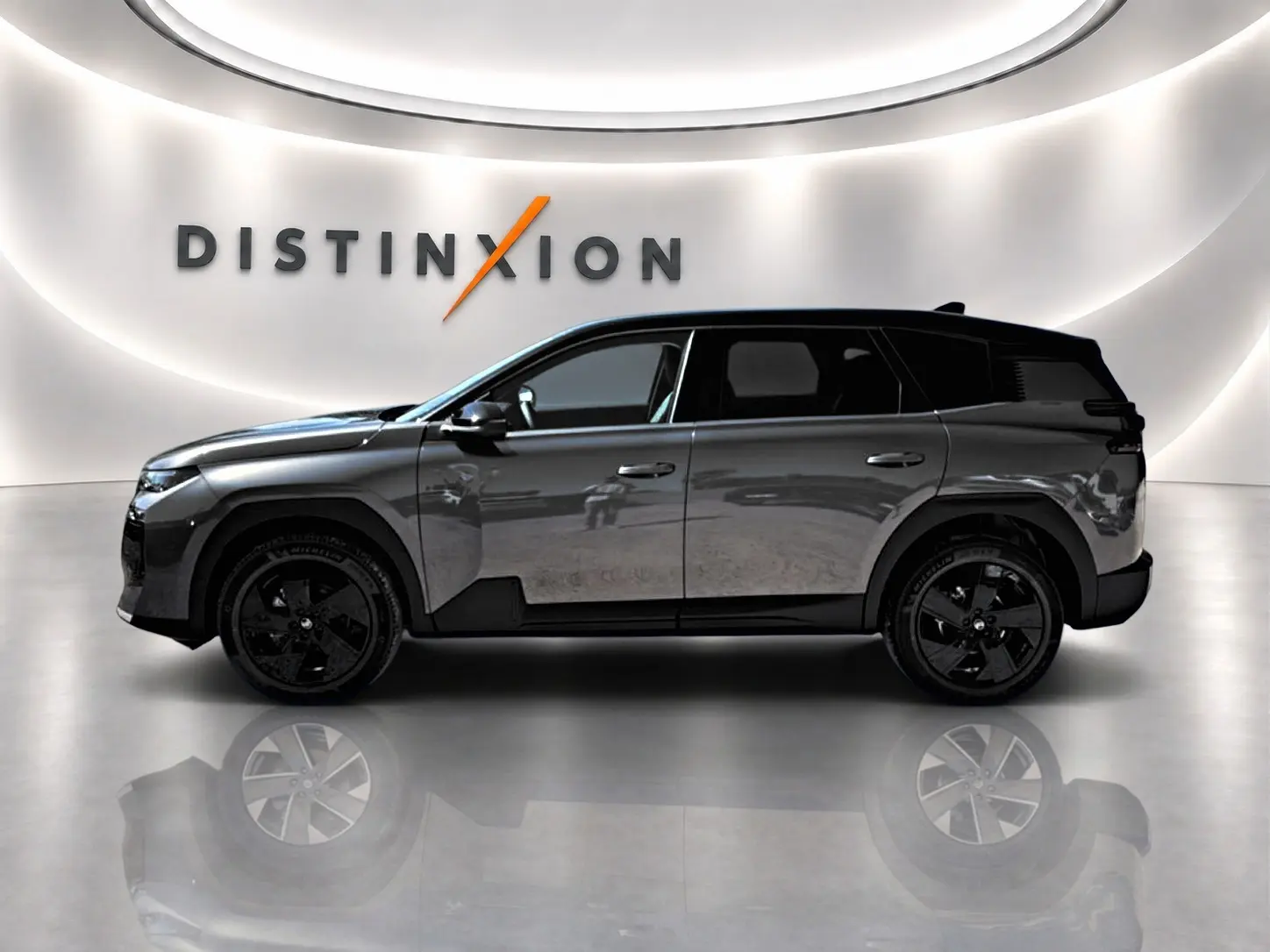 Profil droit du Citroën C5 Aircross 2026 gris platinium avec toit noir et jantes alliage noires dans un showroom lumineux.