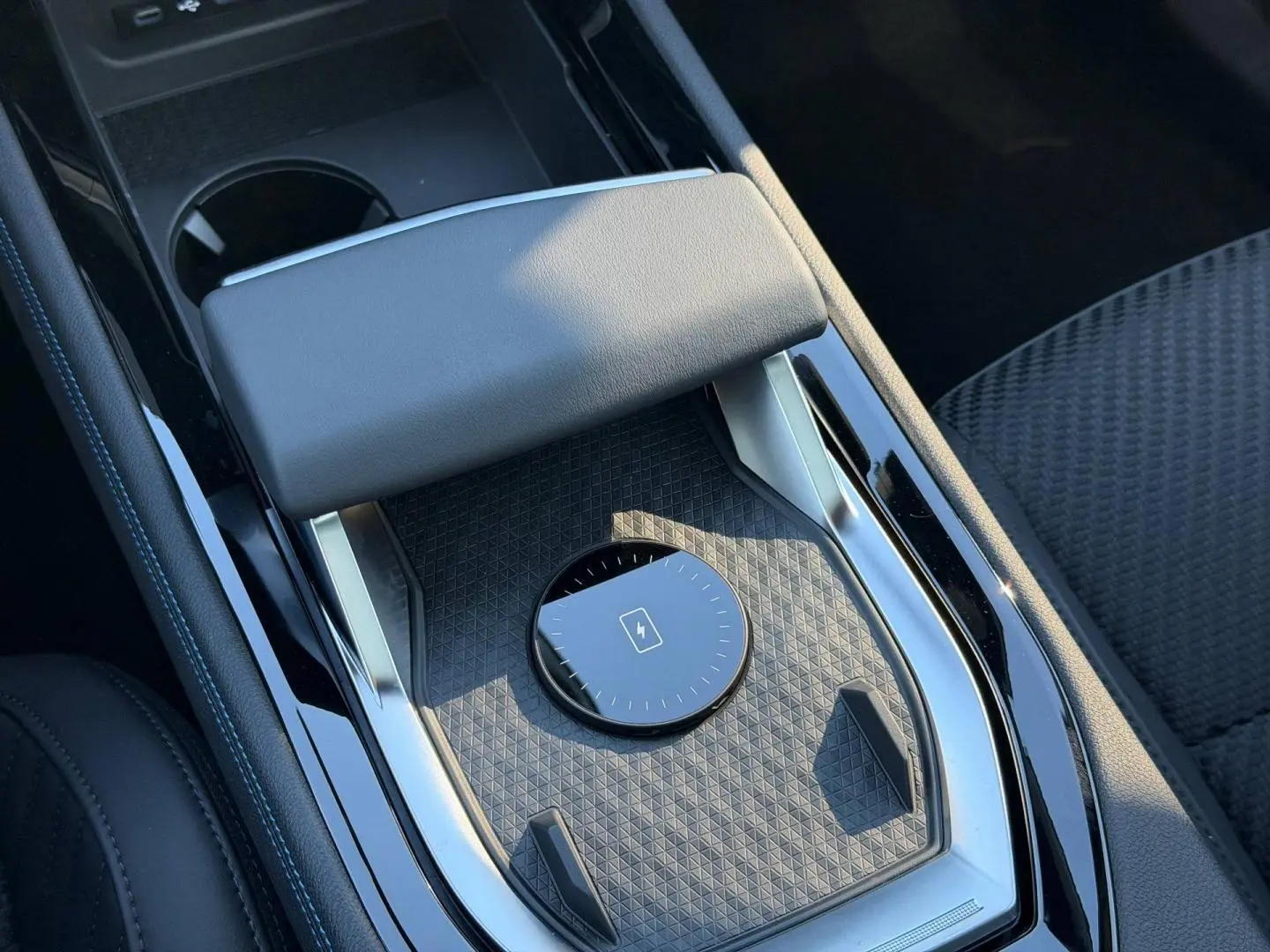 Gros plan sur la console centrale noire étoilé métallisé du Renault Austral avec accoudoir et surface texturée.