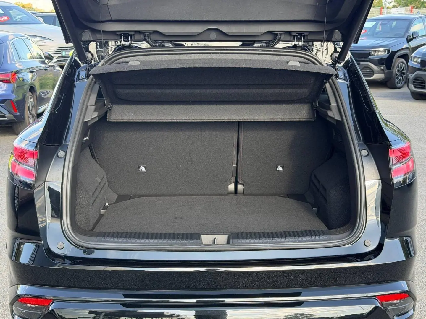 Coffre ouvert vu de l'arrière d'un Renault Austral noir étoilé métallisé, avec banquette arrière rabattable visible.