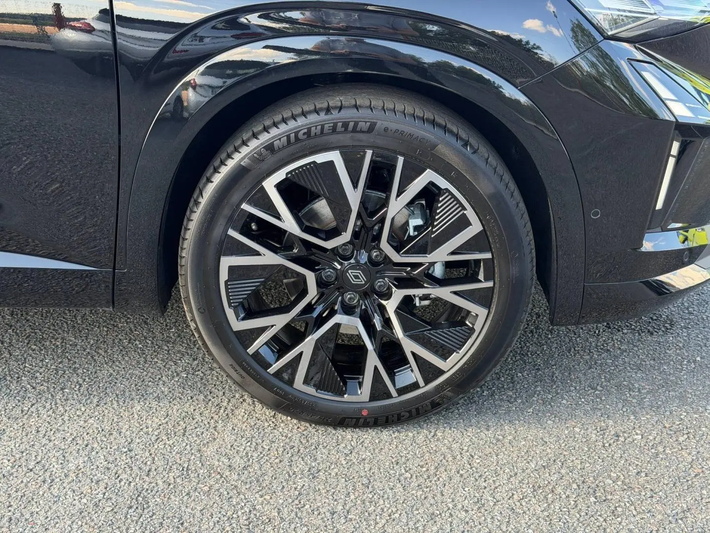 Gros plan sur la roue avant gauche noire étoilé métallisé du Renault Austral 1.2 E-Tech avec jante alu au design géométrique.