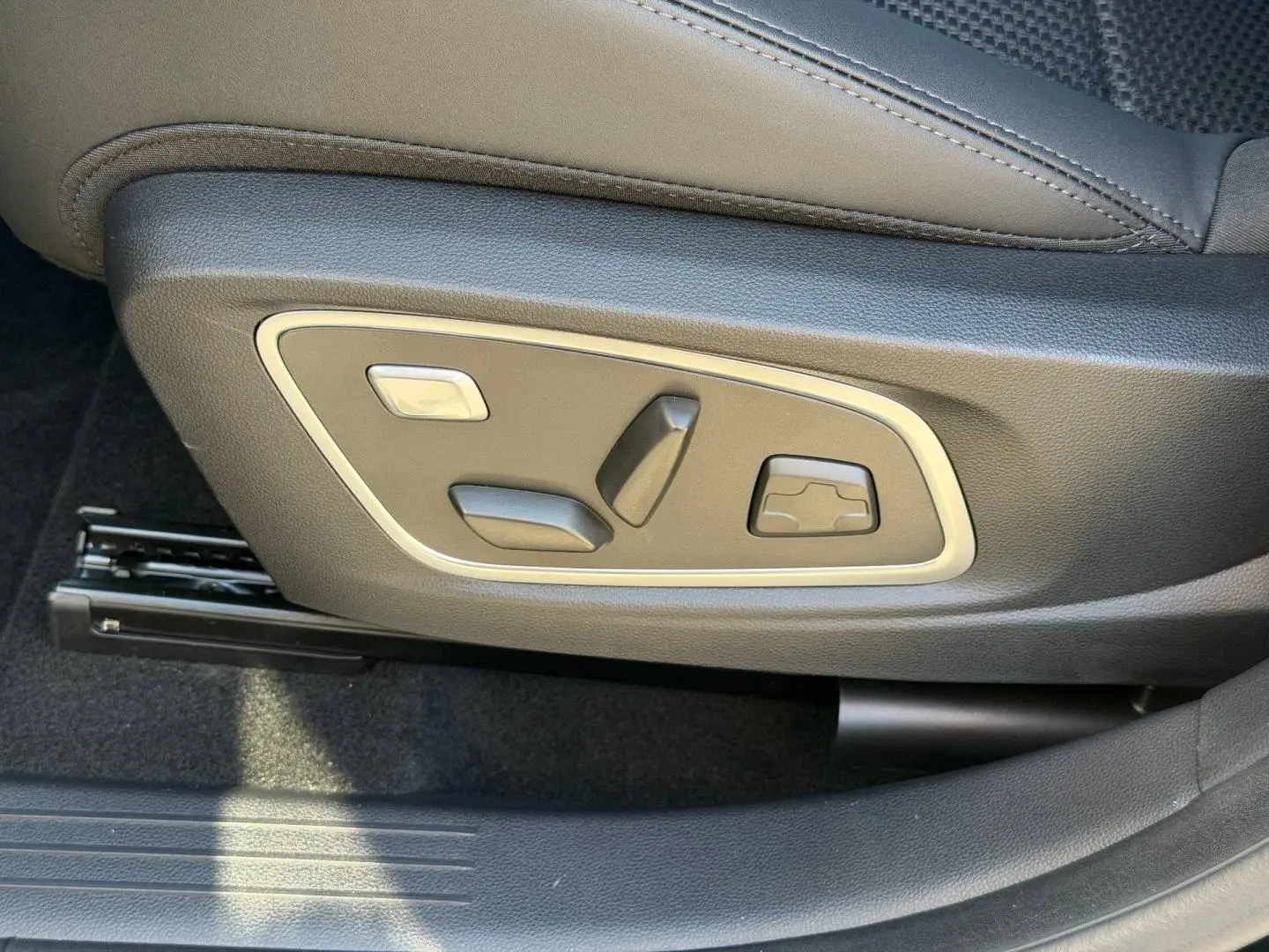 Gros plan sur les commandes électriques de réglage du siège conducteur du Renault Austral noir étoilé.