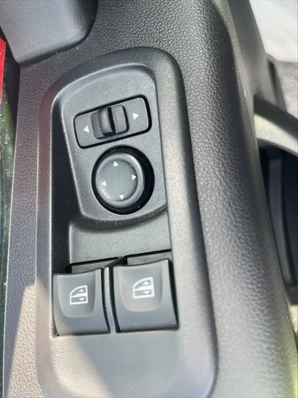 Gros plan sur les commandes de réglage des rétroviseurs et des vitres électriques côté conducteur du Renault Master blanc 2021.