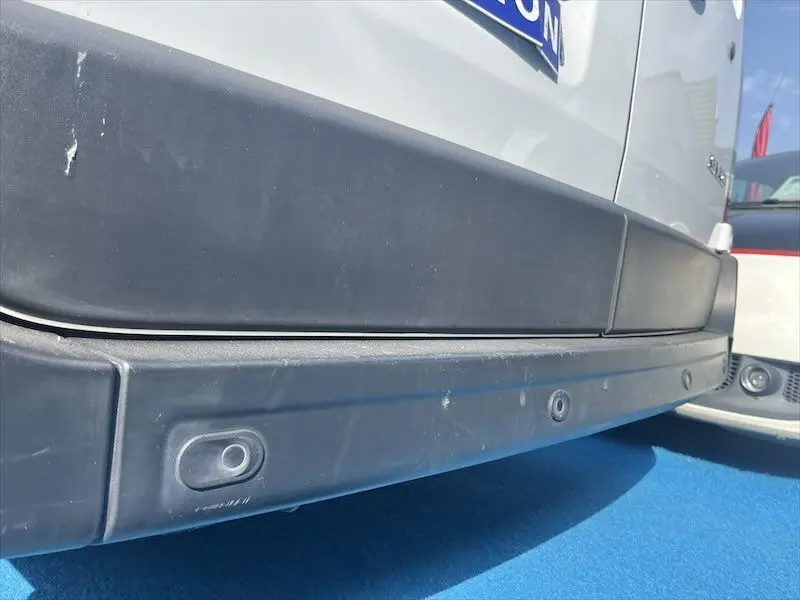 Gros plan sur le pare-chocs arrière noir du Renault Master blanc, montrant les capteurs de recul intégrés.