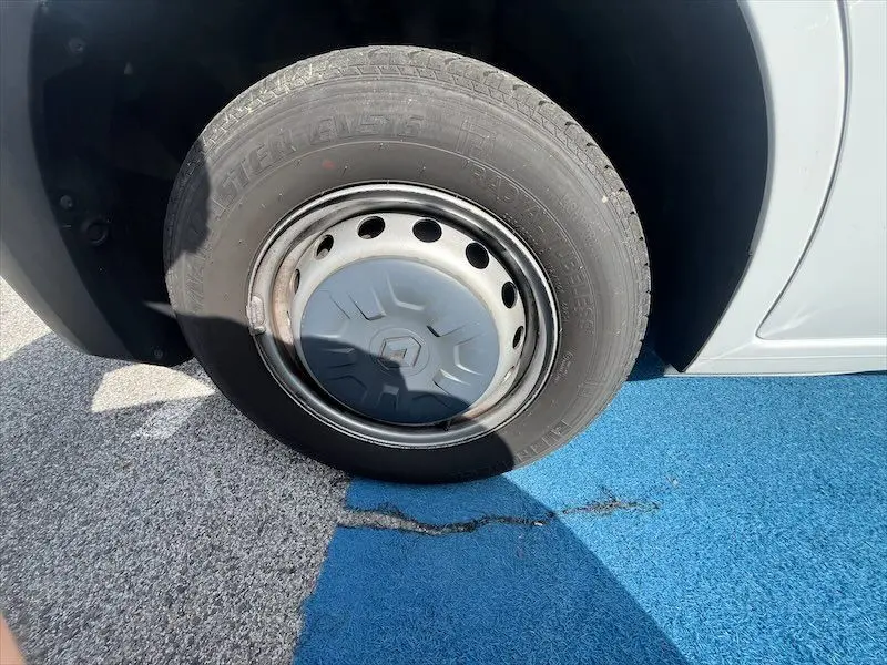 Gros plan sur la roue avant gauche blanche d’un Renault Master 2.3 DCI 135, jante acier avec enjoliveur Renault.