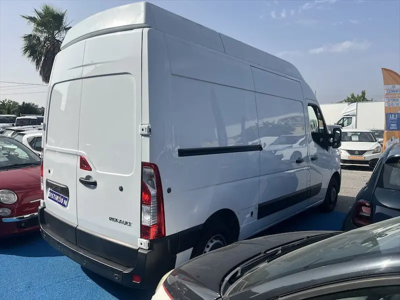 Renault Master blanc en vue 3/4 arrière droit, fourgon grand volume avec toit surélevé et feux arrière verticaux.