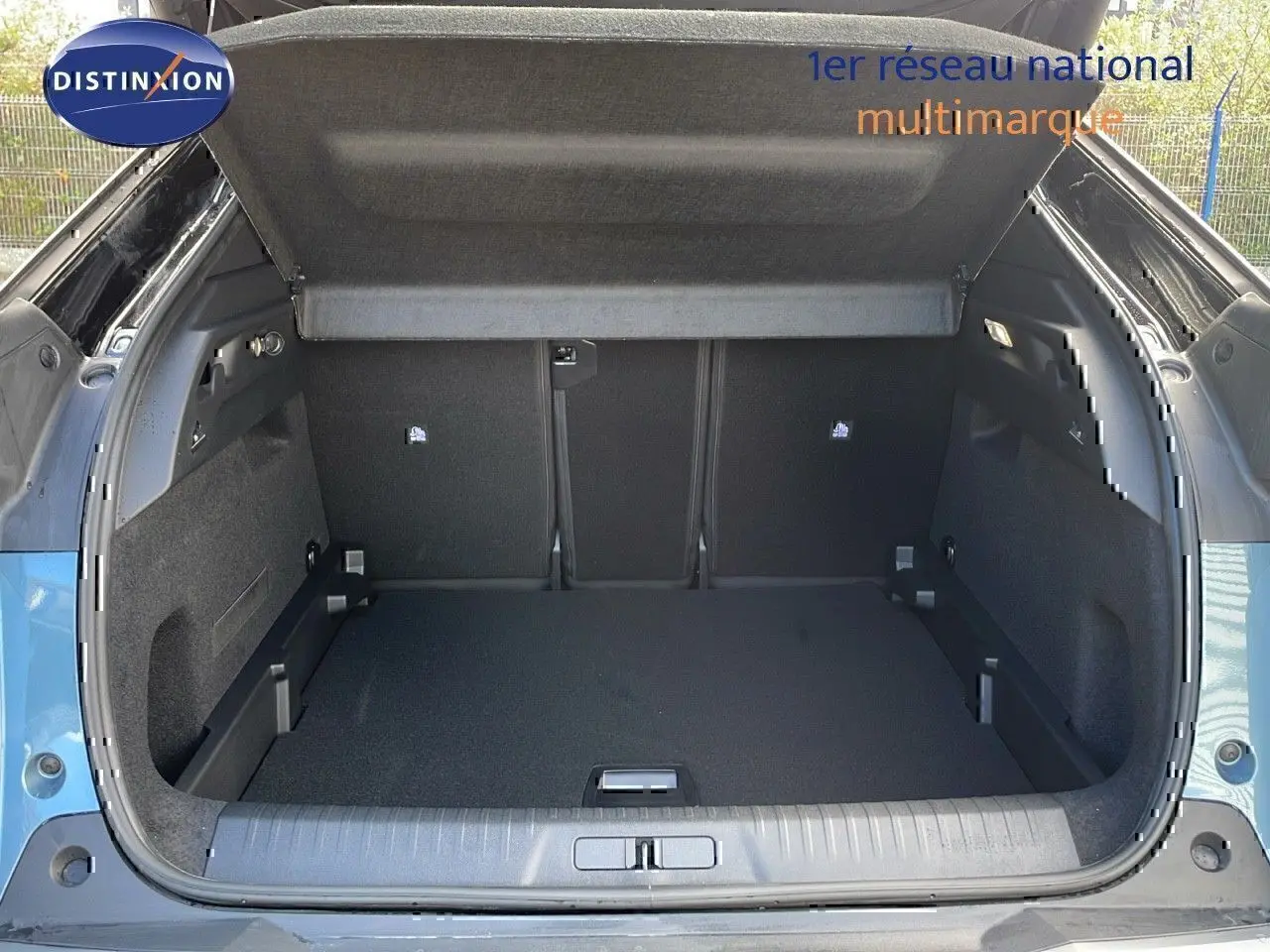 Coffre ouvert d’un Peugeot 3008 1.2 Hybrid 136ch GT bleu Ingaro métal avec toit noir, vue arrière dégagée.