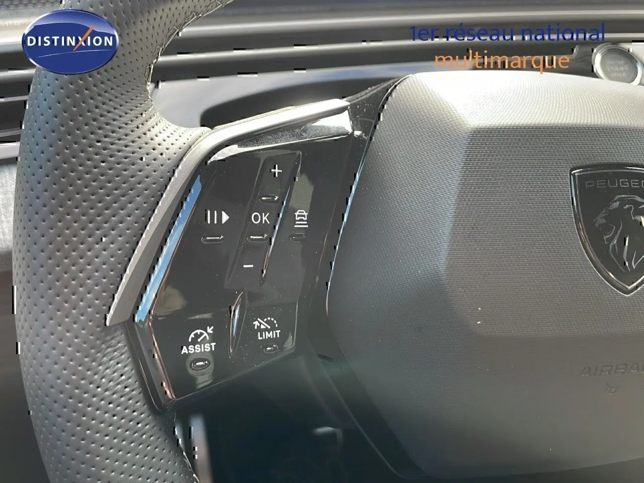 Gros plan sur le volant noir perforé du Peugeot 3008 2025 avec commandes intégrées et logo lion au centre.