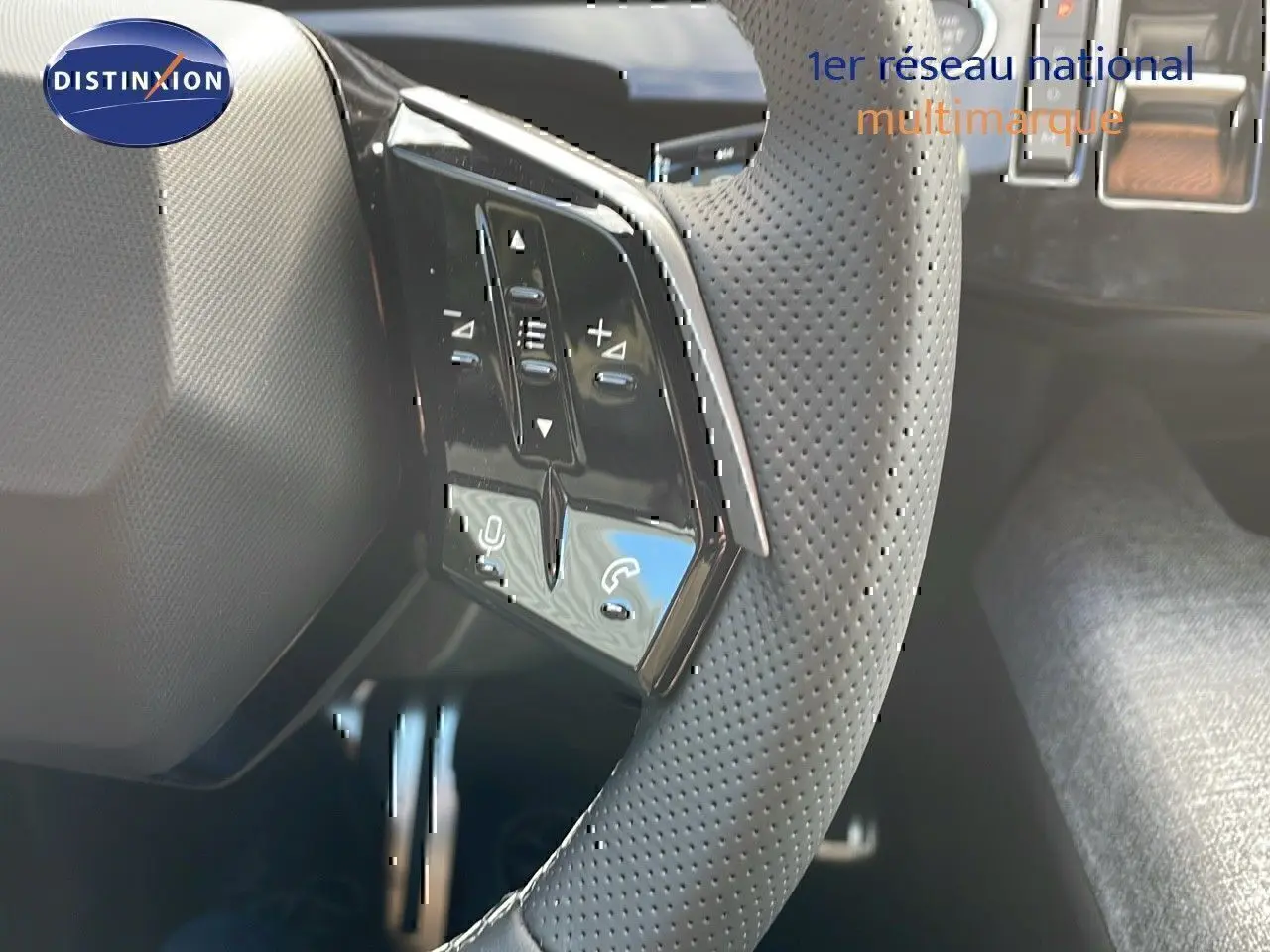 Gros plan sur le volant perforé avec commandes intégrées du Peugeot 3008 1.2 Hybrid 136ch GT, intérieur noir.