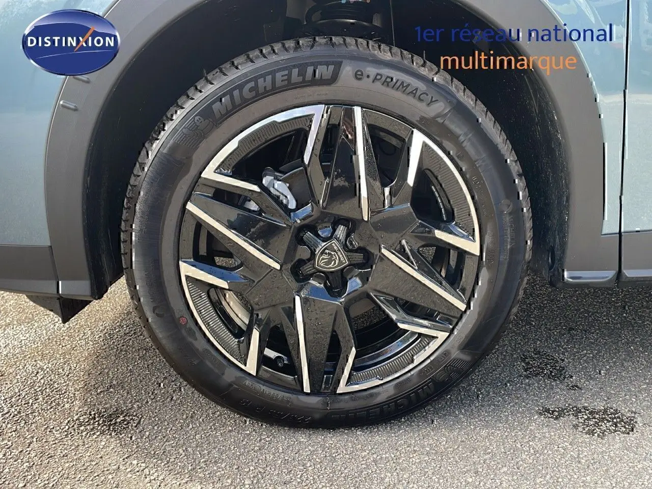 Gros plan sur la roue avant gauche du Peugeot 3008 1.2 Hybrid 136ch GT bleu Ingaro métal avec jante alliage noire et argentée.