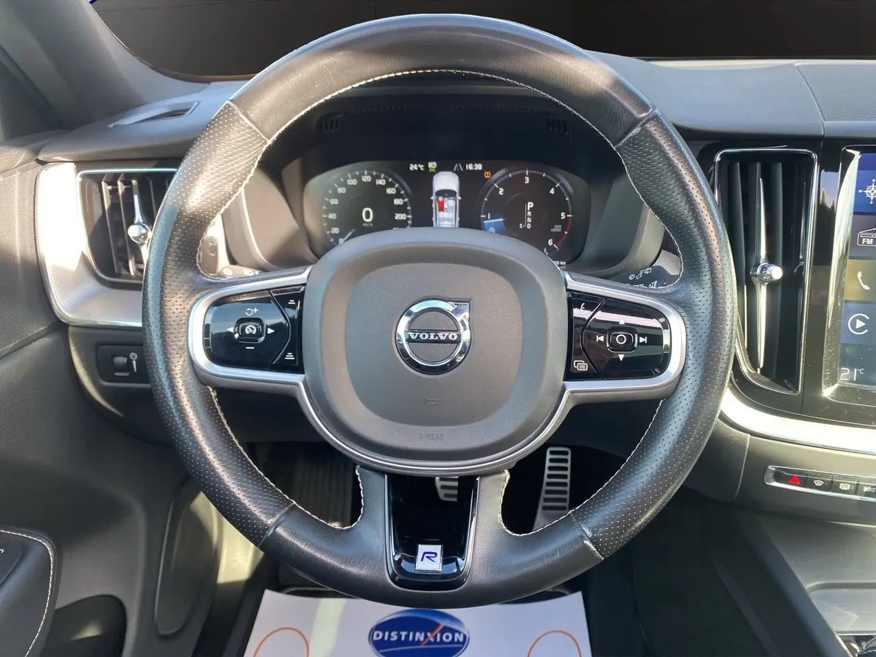 Vue rapprochée du volant cuir noir perforé du Volvo XC60 D4 2019 avec tableau de bord numérique et console centrale visible.