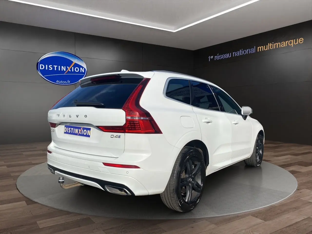 Vue 3/4 arrière droite d'un Volvo XC60 blanc 2019 avec jantes noires et feux arrière LED distinctifs.