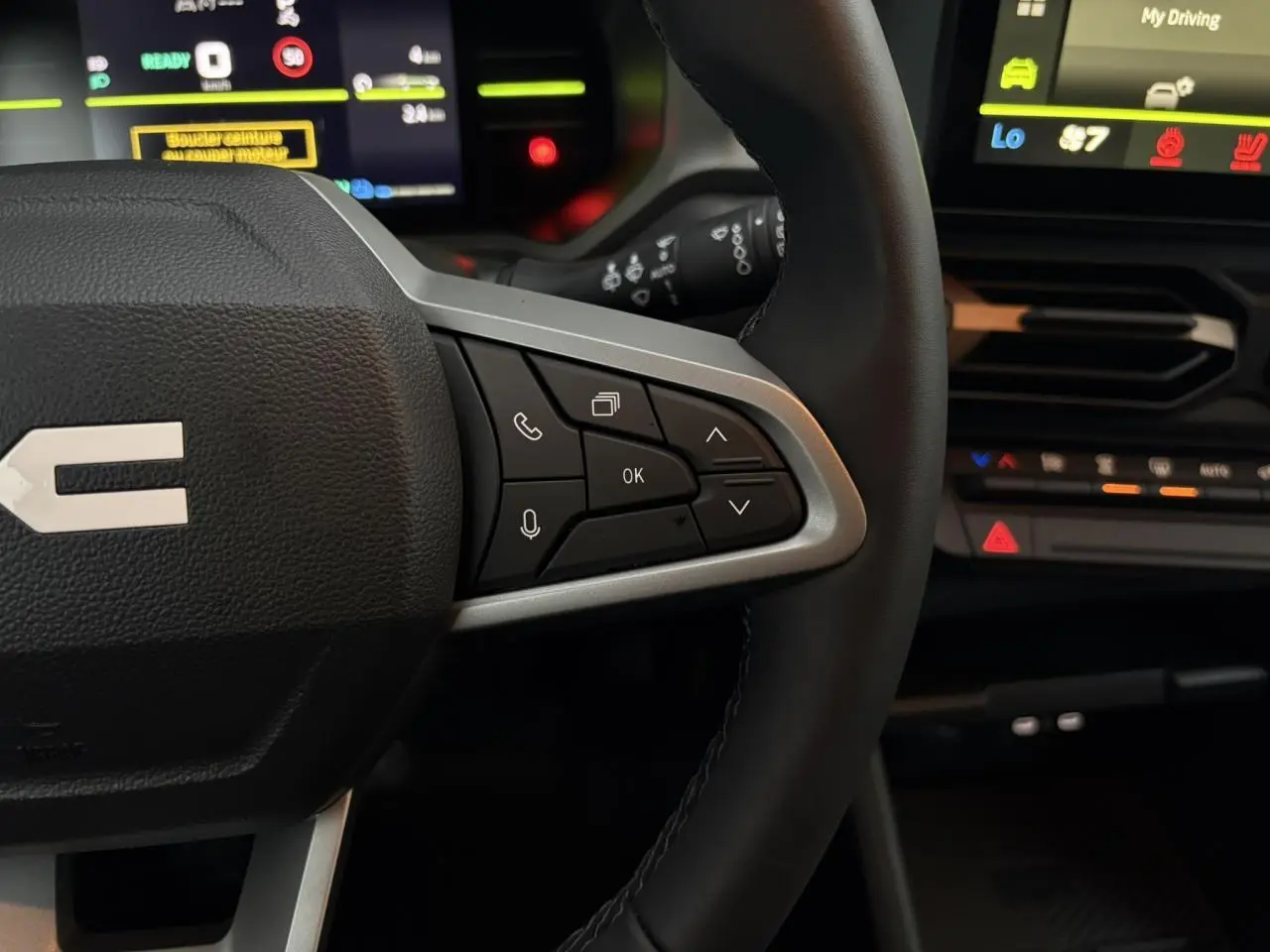 Gros plan sur le volant noir avec commandes multifonctions et tableau de bord digital du Dacia Duster 2026.