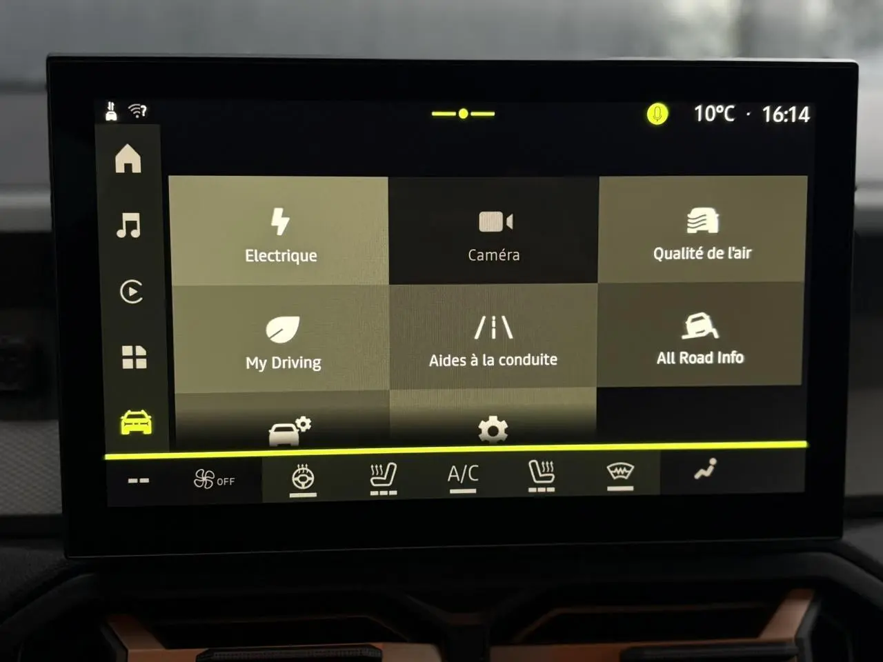 Écran tactile central du tableau de bord du Dacia Duster blanc glacier, affichant les options d’aides à la conduite et climatisation.