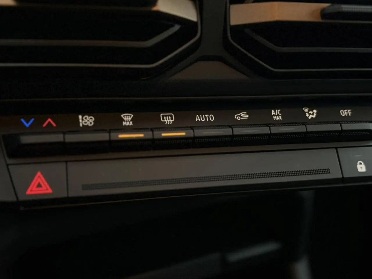 Détail du tableau de bord du Dacia Duster 2026, montrant les commandes de climatisation et d'alerte en lumière ambiante.