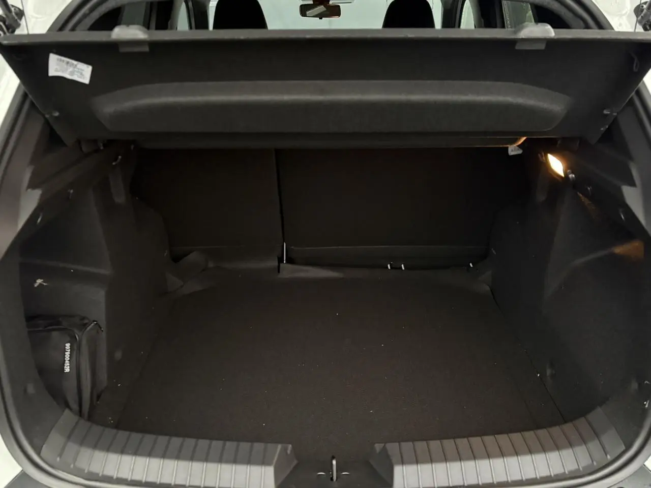 Coffre ouvert du Dacia Duster blanc Glacier, vue intérieure montrant un espace de chargement vide et éclairé.