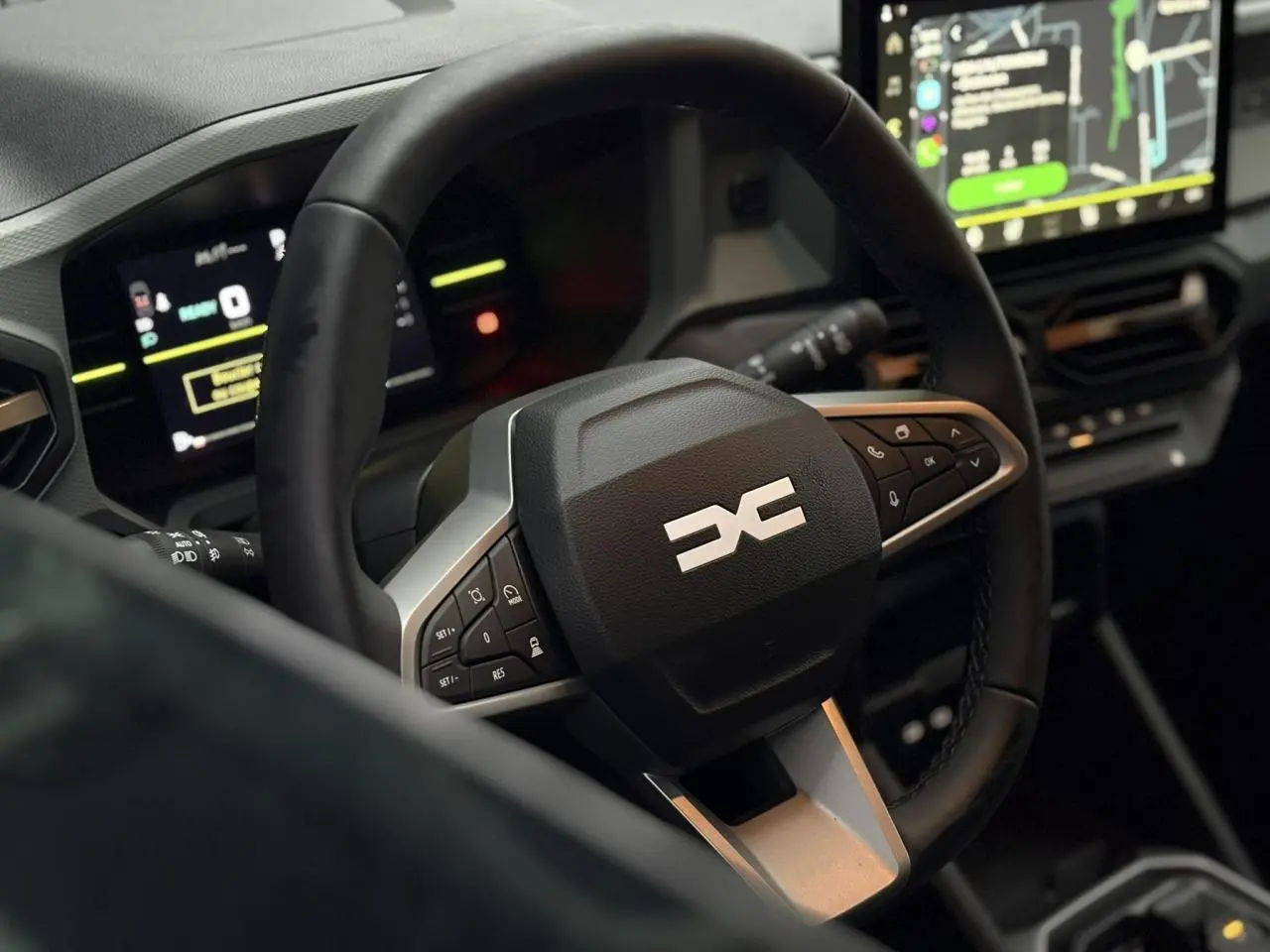 Vue rapprochée du volant multifonctions noir avec logo DACIA et tableau de bord digital du Dacia Duster 2026.
