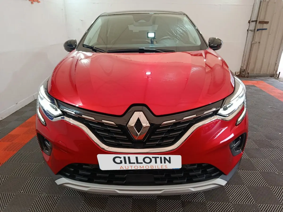Vue frontale d'un Renault Captur Techno TCe 90 rouge avec calandre noire et phares LED allumés.