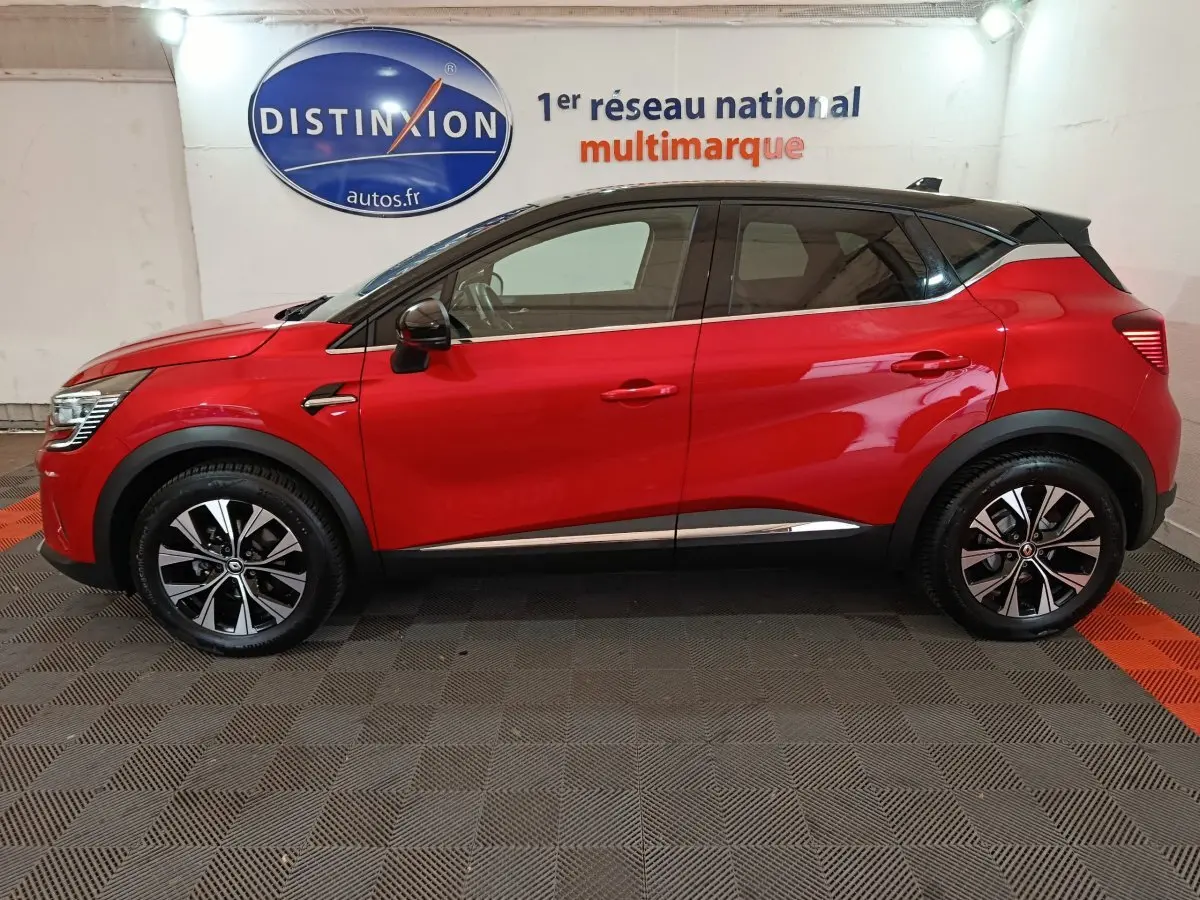 Profil droit d'un Renault Captur Techno TCe 90 rouge 2024 avec toit noir et jantes alliage bicolores.