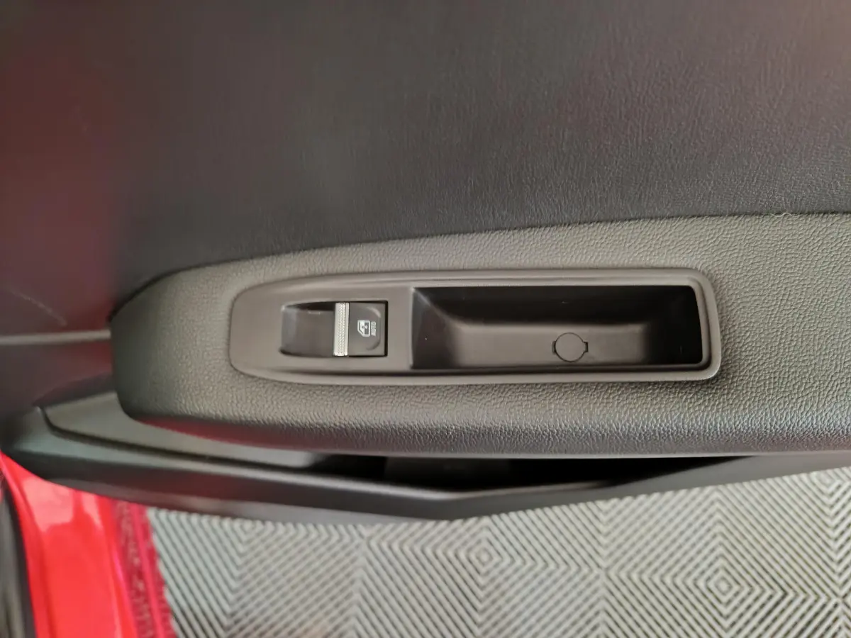 Commande de lève-vitre sur la porte avant gauche rouge d’un Renault Captur techno TCe 90 2024.