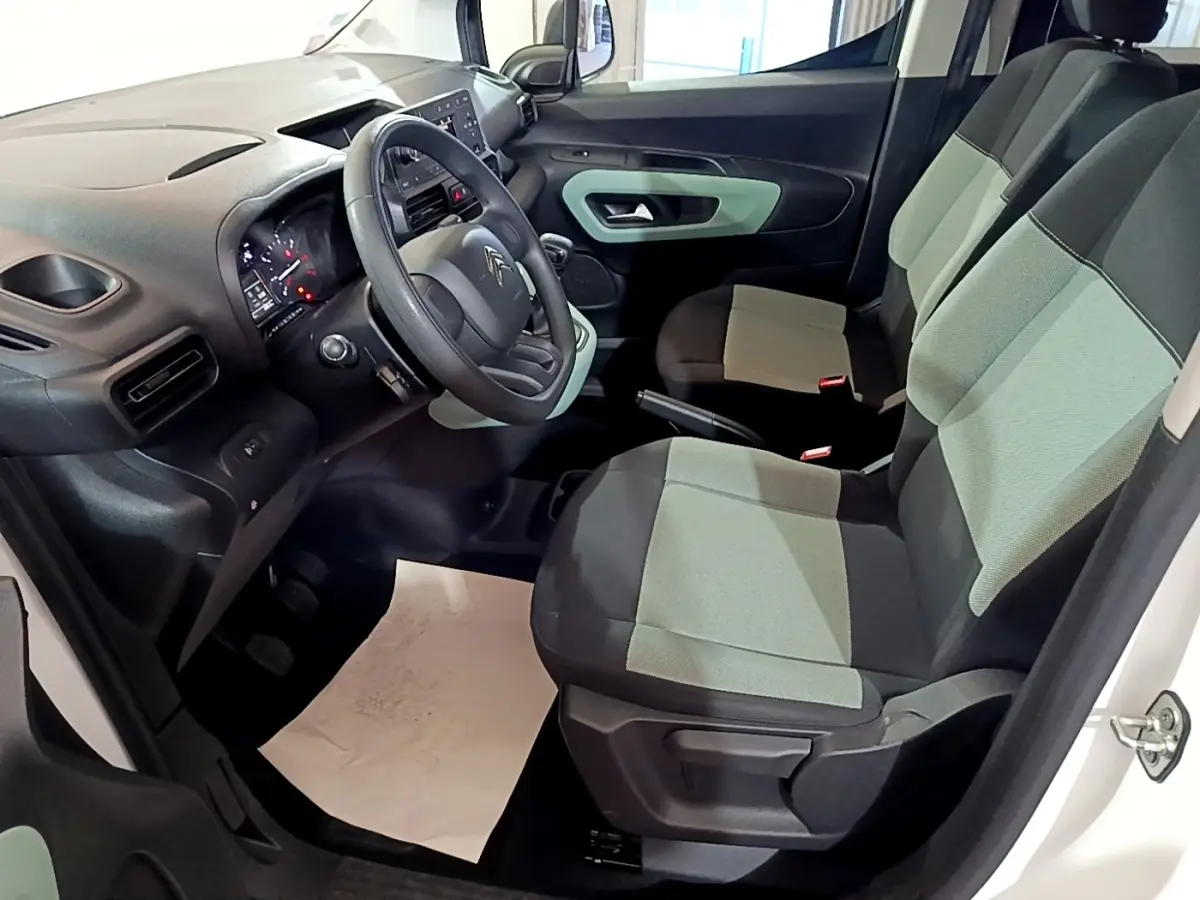 Vue intérieure côté conducteur du Citroën Berlingo blanc 2019, sièges bicolores gris et noir, tableau de bord moderne.