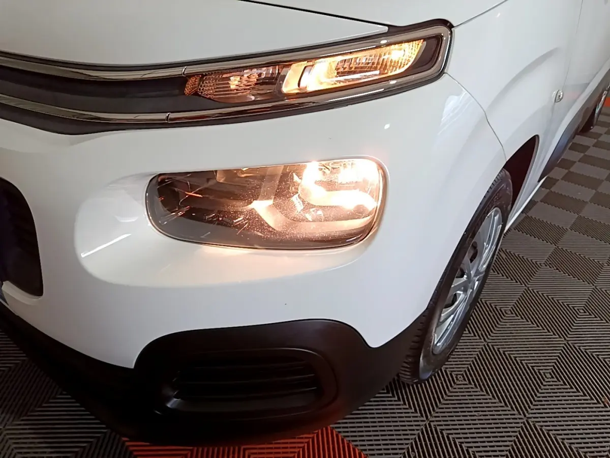 Gros plan sur l'avant droit blanc du Citroën Berlingo XL 2019 avec phare et clignotant allumés.