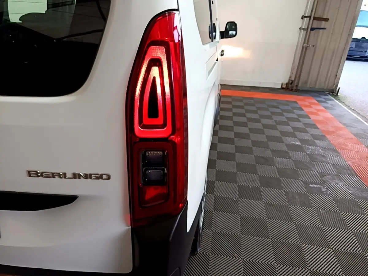 Vue arrière côté gauche d'un Citroën Berlingo blanc XL avec feu arrière allumé dans un garage.