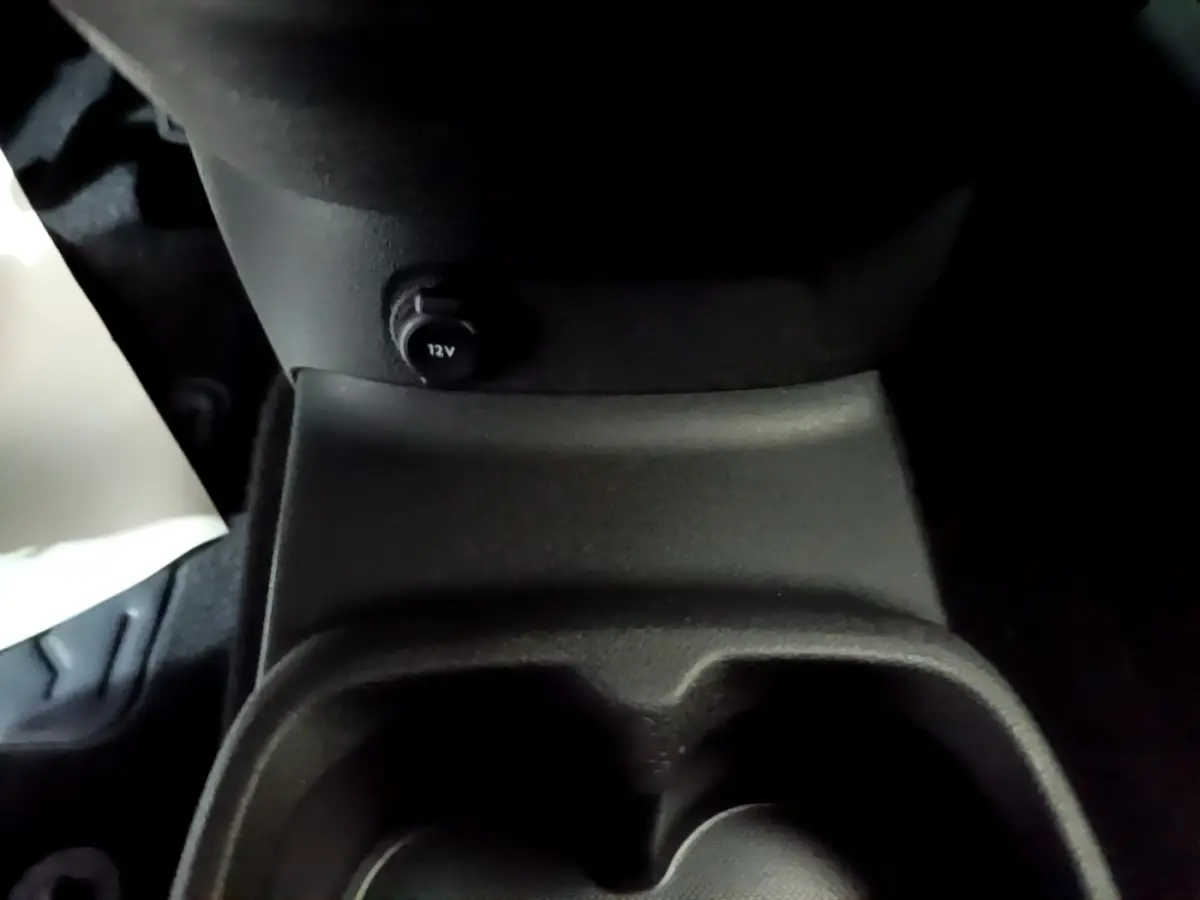 Prise 12V et porte-gobelets en plastique noir dans l'habitacle du Citroën Berlingo XL blanc, vue rapprochée intérieure.