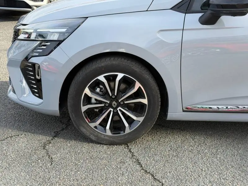 Gros plan sur la roue avant gauche et le pare-chocs avant gris Rafale de la Renault Clio 1.6 E-Tech hybride 2025.