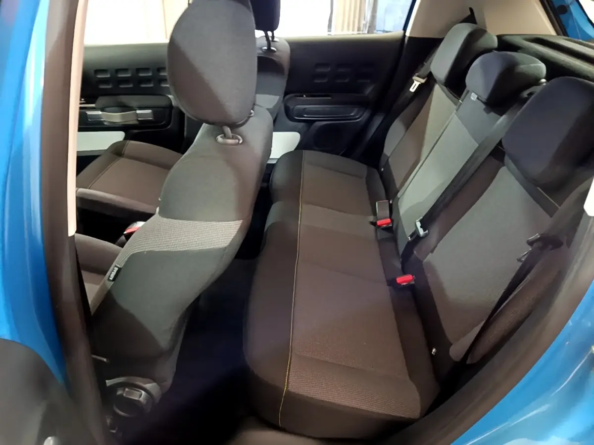 Vue intérieure côté droit sur les sièges arrière gris foncé d’une Citroën C3 bleu 2017 avec portes ouvertes.