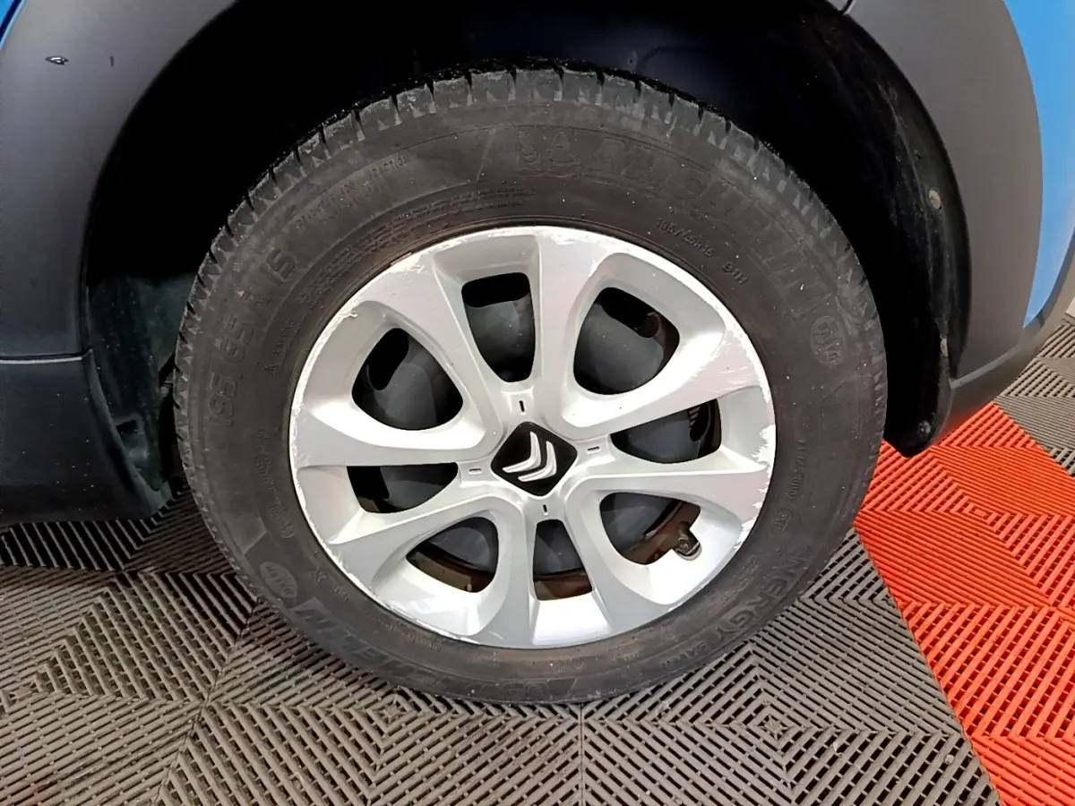 Gros plan sur la roue avant droite d’une Citroën C3 bleu, jante alliage argentée avec logo Citroën central.