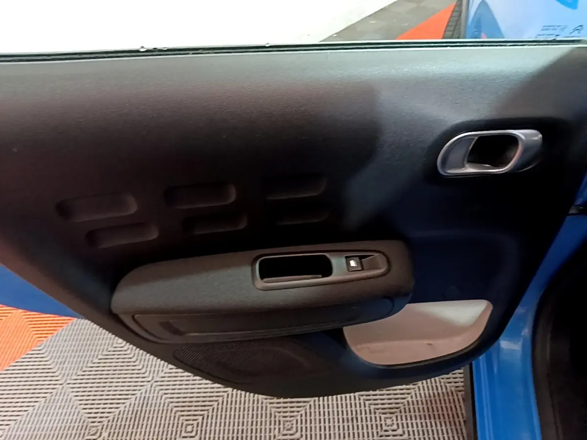Vue intérieure de la porte avant gauche bleu de la Citroën C3 2017 avec poignée et commande de vitre électrique.