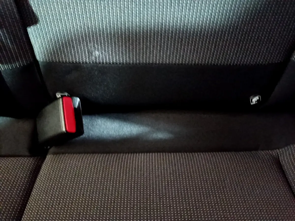 Gros plan sur la banquette arrière grise de la Citroën C3 avec boucle de ceinture de sécurité rouge visible.