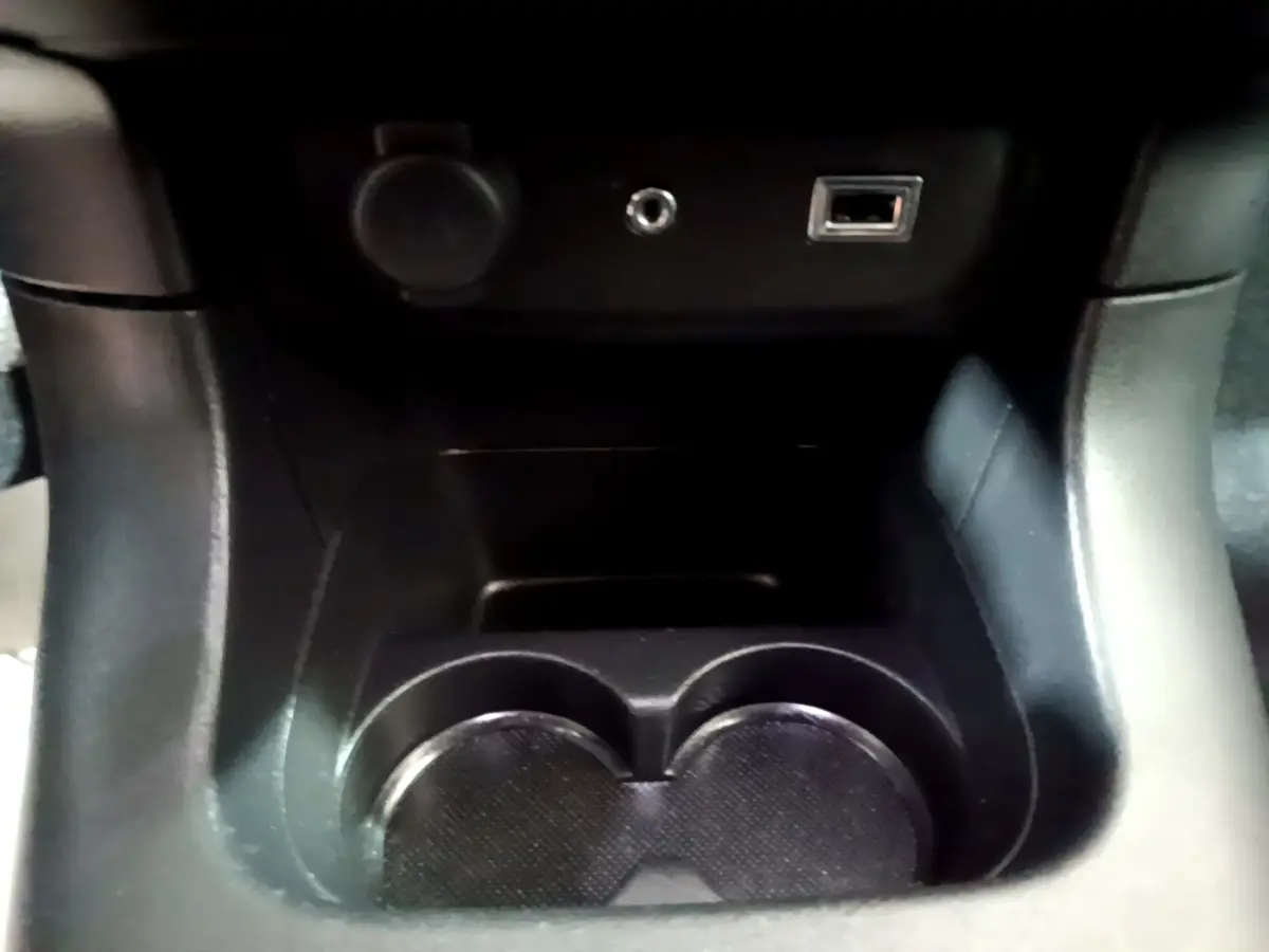 Gros plan sur la console centrale noire de la Citroën C3 2017, montrant porte-gobelets et prises USB et auxiliaire.