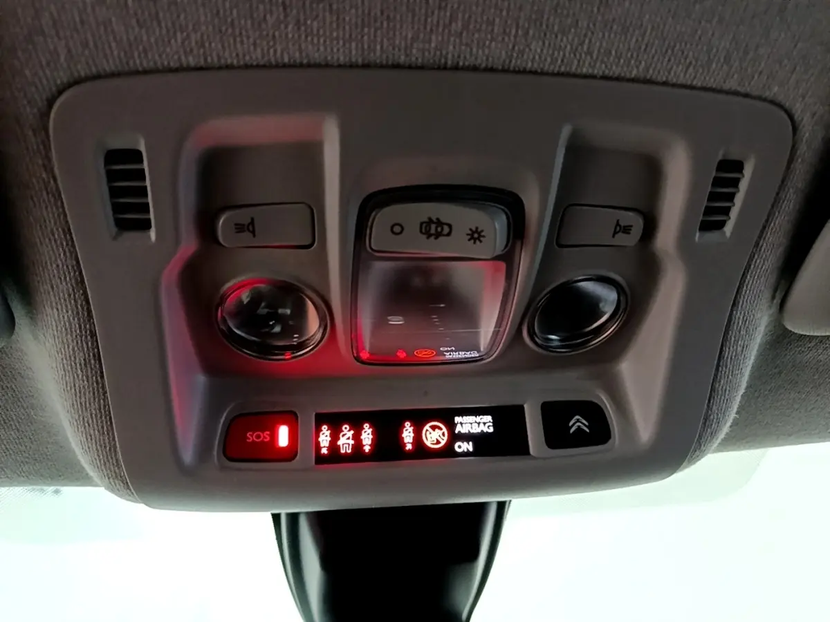 Vue intérieure du plafonnier de la Citroën C3 bleu, avec boutons d’éclairage et indicateurs lumineux rouges allumés.