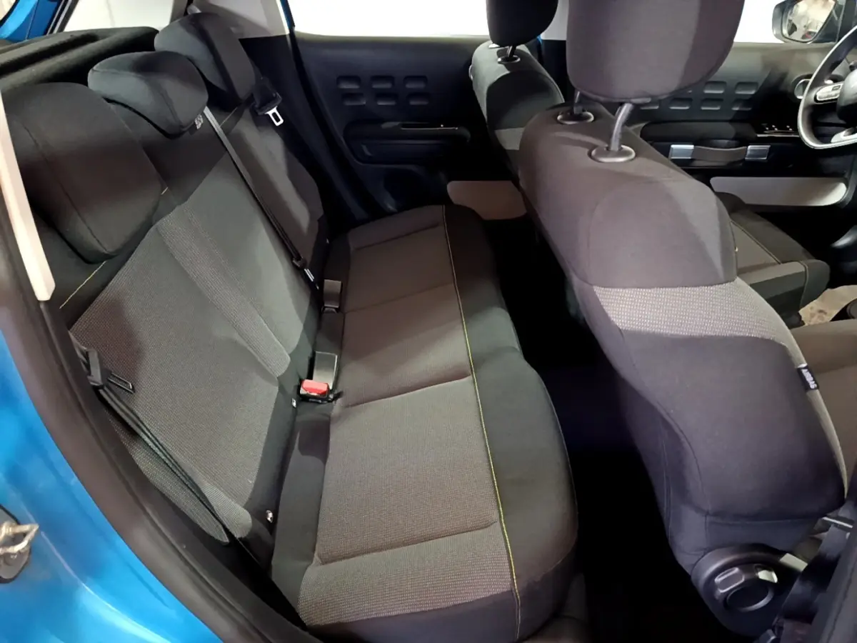 Vue intérieure arrière côté gauche de la Citroën C3 bleu, montrant la banquette arrière et les sièges avant en tissu noir.