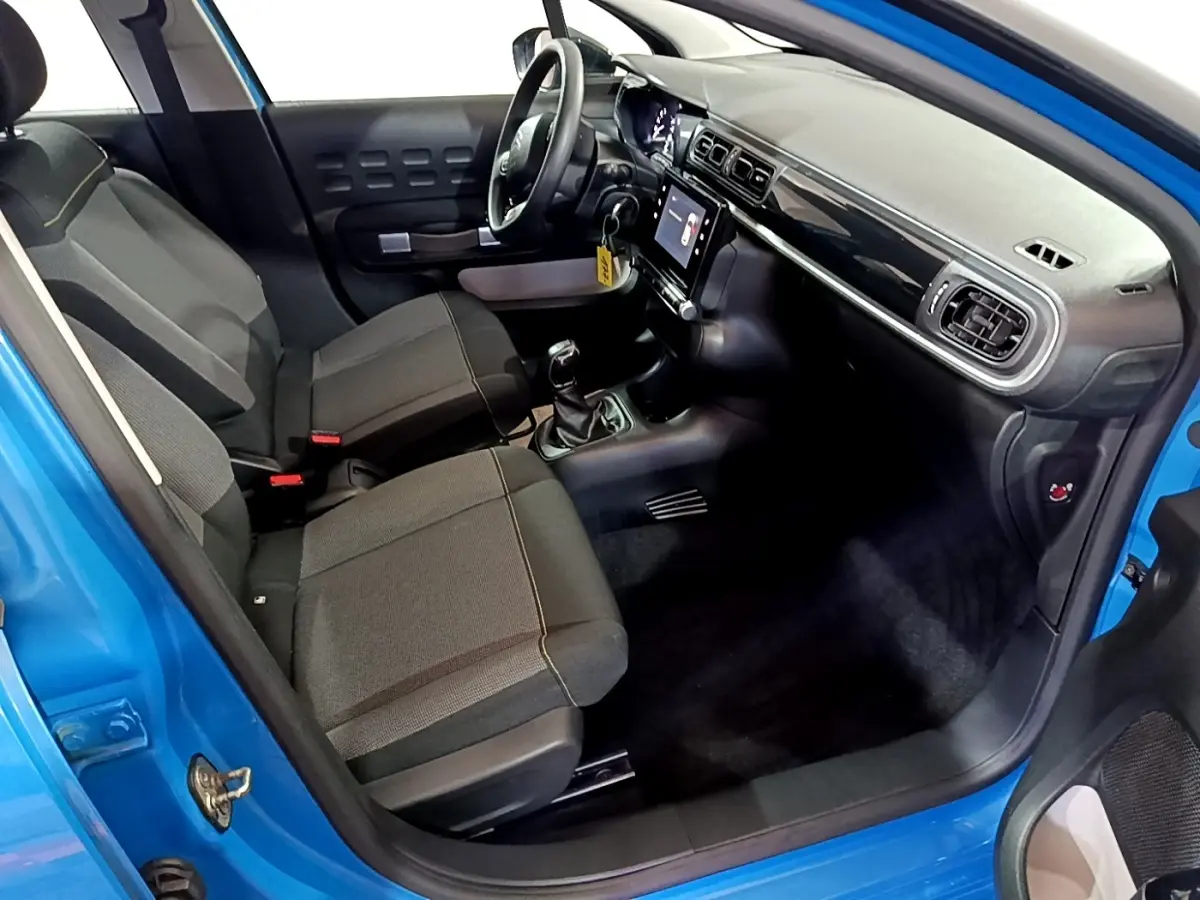 Vue intérieure côté conducteur d'une Citroën C3 bleu 2017, montrant sièges noirs et tableau de bord avec écran tactile.