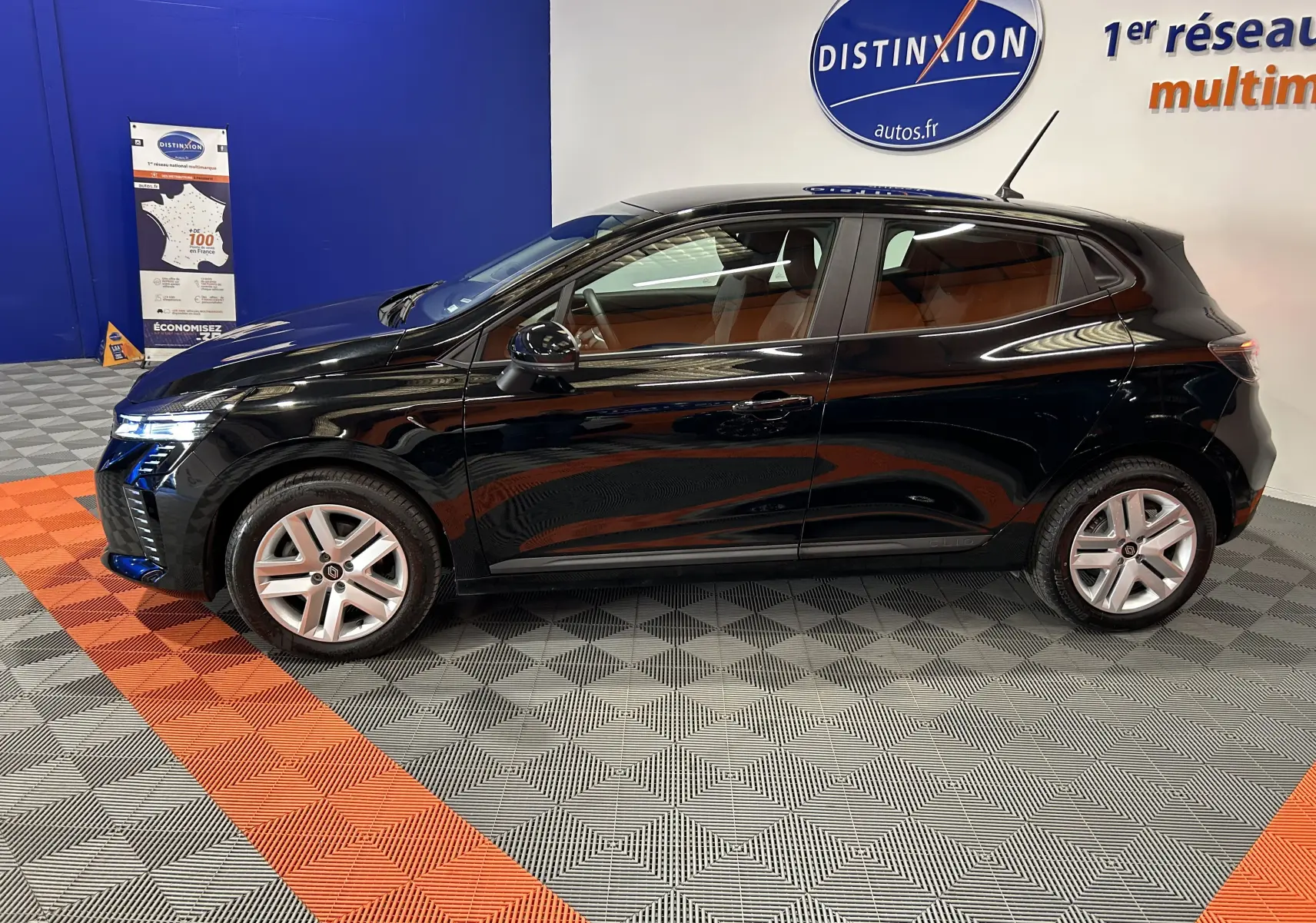 Profil latéral gauche d'une Renault Clio V noire, en intérieur, avec jantes alliage et vitres teintées.